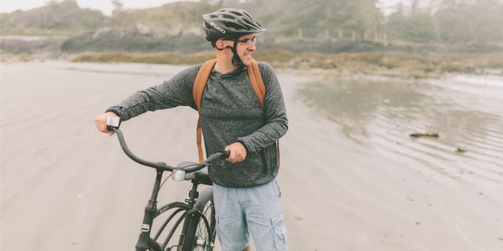 Man with a bicycle on a foggy beach