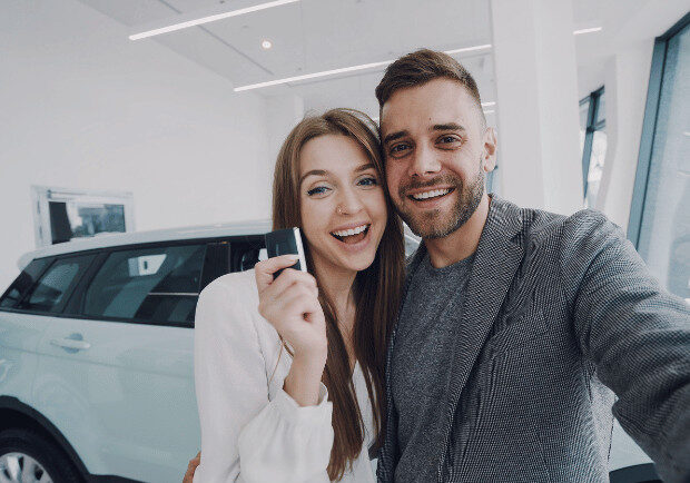 Young couple with keys to new car.